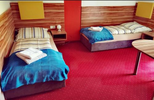 two beds in a room with red carpet at Holding in Tulln