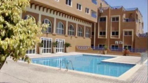 a swimming pool in front of a large building at Islan bay apartment in Agadir