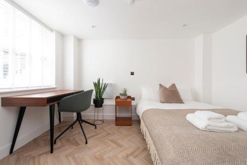 1 dormitorio con 2 camas, escritorio y escritorio en Cityscape Charm Studio - Central London, en Londres