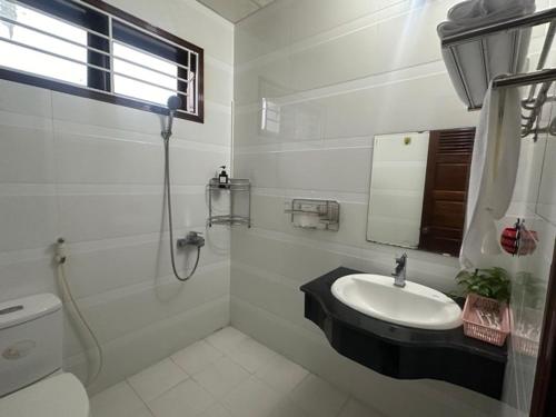uma casa de banho branca com um lavatório e um WC em RUBY HOMESTAY em Hue