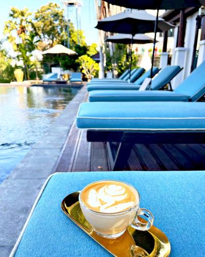 a cup of coffee sitting on a table next to a pool at Buri Sriping Riverside Resort & Spa in Chiang Mai