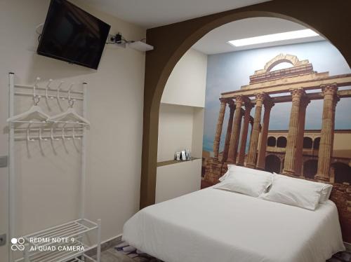 a bedroom with a bed and a tv on a wall at ERES EMÉRITA "Apartamentos & Suites" in Merida