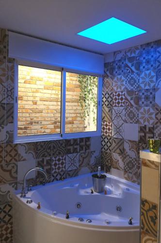 a bathroom with a tub with a light on the ceiling at ERES EMÉRITA "Apartamentos & Suites" in Merida