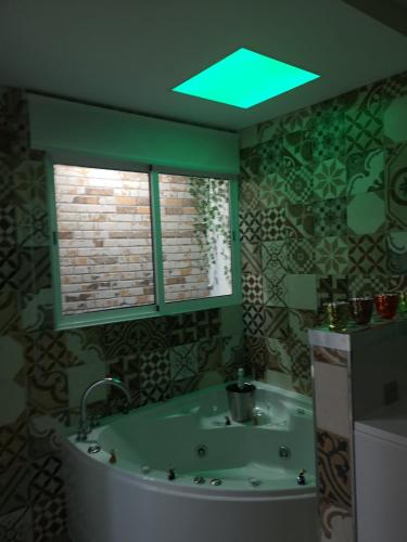 a bathroom with a tub and a green light at ERES EMÉRITA "Apartamentos & Suites" in Merida