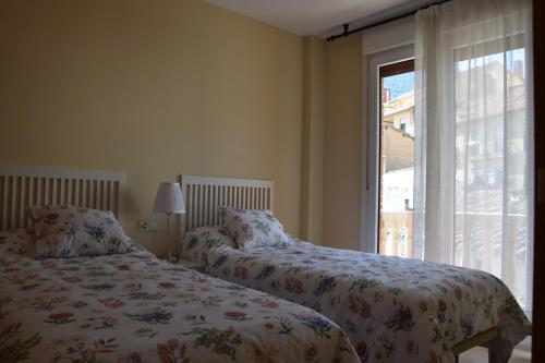 2 camas en un dormitorio con ventana en La abuela Isabel Piso con encanto Arnedillo, en Arnedillo