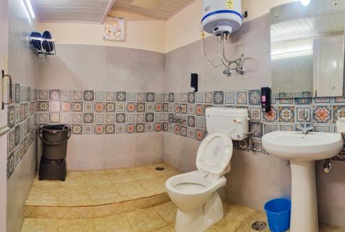 a bathroom with a toilet and a sink at Giggling Goons Cabins & Kitchen in Kasol