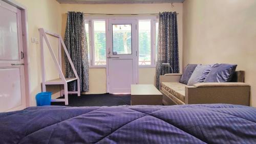 a bedroom with a bed and a couch and a window at Giggling Goons Cabins & Kitchen in Kasol
