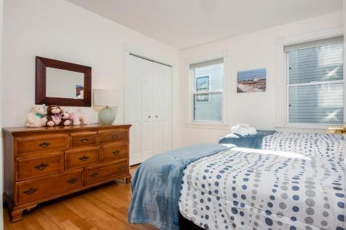 a bedroom with a bed and a dresser with a mirror at Steps to Downtown Rooftop Deck Flexible Temp Stay in Newburyport