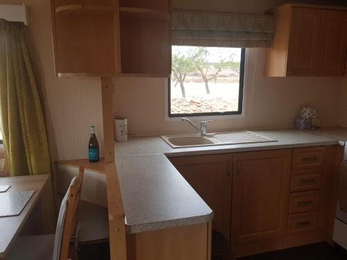 una pequeña cocina con fregadero y ventana en Pinoso Mountain View Mobile Home Alicante Med Syndicate 4, en Murcia