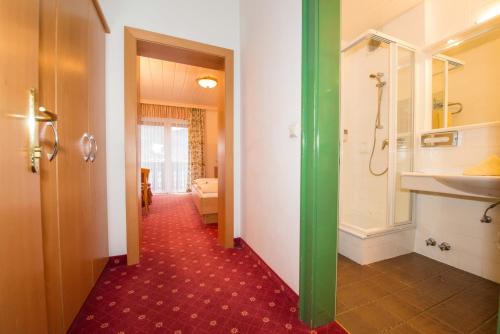 a bathroom with a walk in shower and a sink at LACUS Hotel am See in Weissensee