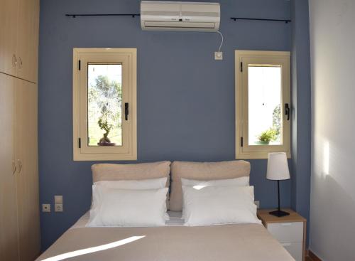 a bedroom with blue walls and a bed with two windows at Sunset View Residence in Markópoulon