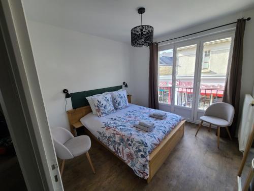 a bedroom with a bed and two chairs and a window at Appartement 2 Chambres INDIaNA Hyper centre in Vitré