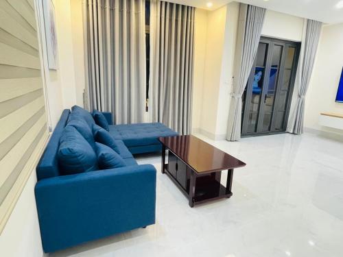 a living room with a blue couch and a coffee table at Holiday Villa Novaworld Phan Thiet in Phan Thiet