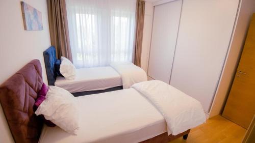 three beds in a small room with a window at Green Ilidza Apartment in Sarajevo