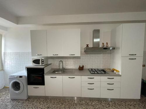 uma cozinha com armários brancos, um lavatório e um micro-ondas em Casa Carmine - Casa Vacanza em Colleberardi