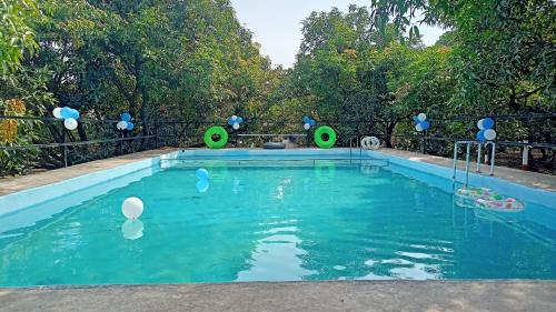 - une piscine avec des ballons blancs et bleus dans l'eau dans l'établissement Renewed Jadeshwar Farm Resort, à Sasan Gir