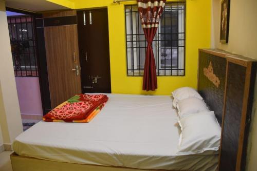 1 cama grande en una habitación con paredes y ventanas de color amarillo. en Amudha Hotels & Restaurant, en Yercaud