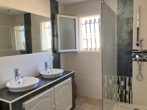 une salle de bain avec deux lavabos et une douche dans l'établissement La villa des Geckos de Mus, à Mus