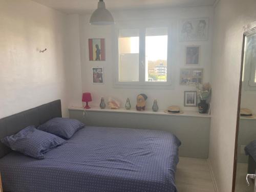 une chambre avec un lit bleu et une fenêtre dans l'établissement Appartement calme et ensoleillé, à Hérouville-Saint-Clair