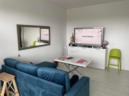 uma sala de estar com um sofá azul e uma televisão em Appartement calme et ensoleillé em Hérouville-Saint-Clair