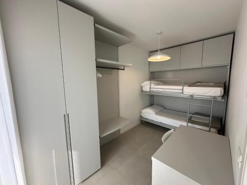 a small white room with a bed and a closet at Woody Green Charming Apartments - Agenzia Cocal in Caorle