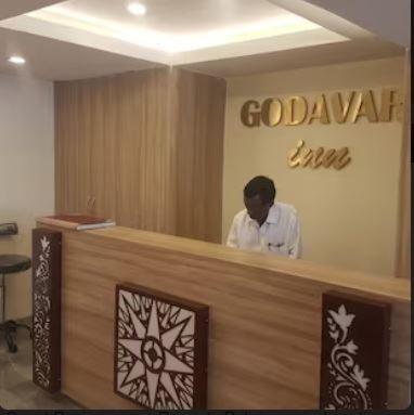 a man standing behind a reception counter in a restaurant at HOTEL GODAVARI INN in Mire