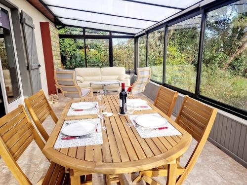 uma mesa de madeira com cadeiras e uma garrafa de vinho em Les Capucines YourHostHelper em Portbail