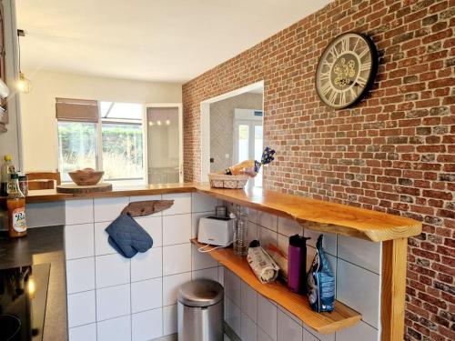 a kitchen with a clock on a brick wall at Les Capucines in Portbail