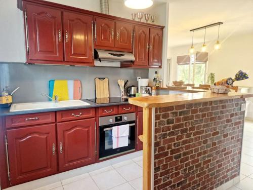 a kitchen with red cabinets and a brick wall at Les Capucines in Portbail