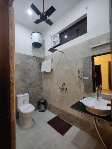 a bathroom with a toilet and a sink with a ceiling fan at Jim's Inn in Rāmnagar