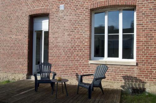 2 sillas y una mesa en una terraza junto a un edificio de ladrillo en Studio calme et cosy au Andelys pour 2 personnes en Les Andelys