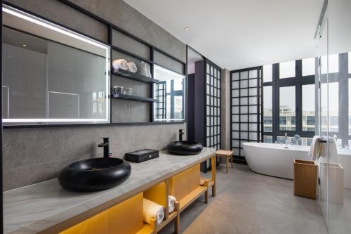 a bathroom with two sinks and a bath tub at GINCO Hotel Guangzhou Baiyun Airport in Guangzhou