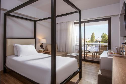 a bedroom with a canopy bed and a balcony at Hersonissos Palace in Hersonissos