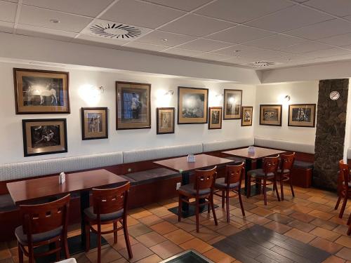 un restaurant avec des tables, des chaises et des photos sur le mur dans l'établissement Pohostinství v Holi, à Průhonice