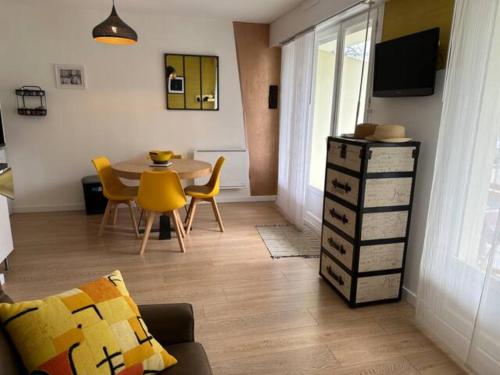 un salon avec une table et des chaises jaunes dans l'établissement Studio La Frégate, à Dinard