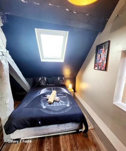 a bedroom with a bed in a attic with a window at Star Wars + Jacuzzi à 10 minutes de Disneyland in Condé-Sainte-Libiaire