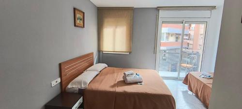 a bedroom with two beds and a large window at Hostal Europa in Tarragona