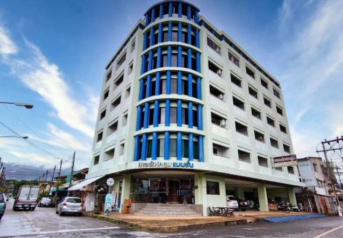 a tall white building with blue windows on a street at Perfectroom Mansion in Hat Yai