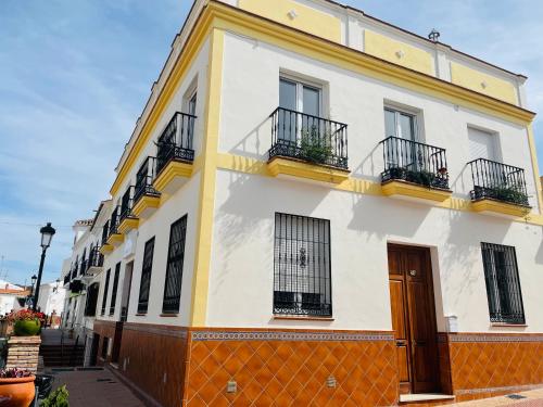 a yellow and white building with balconies on a street at Acantilados De Maro in Maro