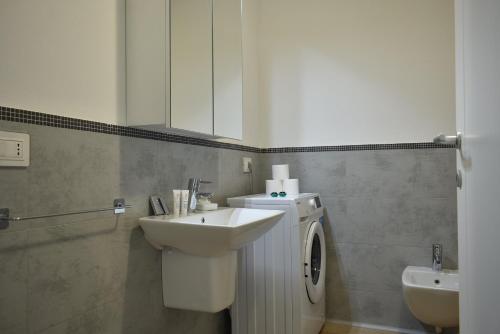 a bathroom with a sink and a washing machine at Welc-ōM Padova Santa Sofia in Padova