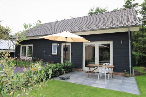 Doornenburg的住宿－bloom-inn gastvrij genieten，一个带桌子和遮阳伞的庭院