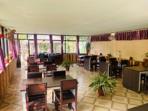 ein Restaurant mit Tischen, Stühlen und Fenstern in der Unterkunft Eco Adventure Resort in Sauraha
