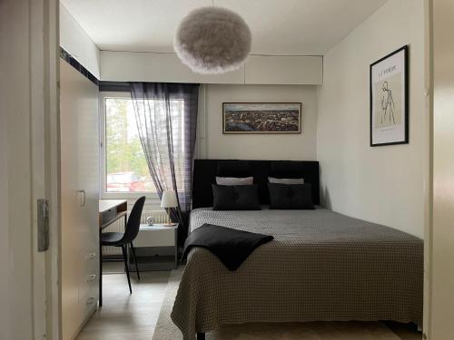 1 dormitorio con cama, mesa y ventana en Rauhallinen rivitalon pääty, en Porvoo