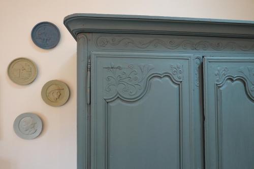 a green cabinet with clocks on the wall at Kermaria Bois D Amour Apartment in Pont-Aven