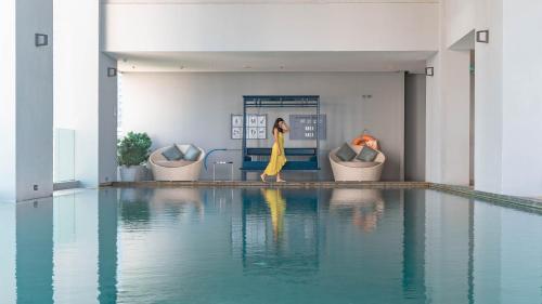 une femme en robe jaune marchant à côté d'une piscine dans l'établissement Jasmine 59 Hotel, à Bangkok