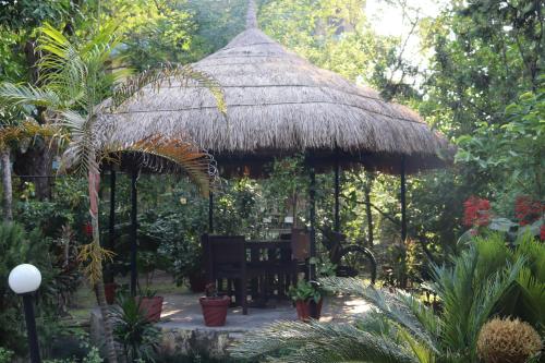 einen Pavillon mit einem Stuhl und einer Strohhütte in der Unterkunft Eco Adventure Resort in Sauraha