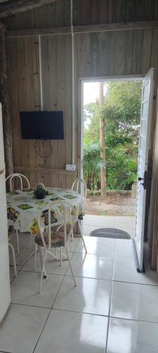 une salle à manger avec une table, des chaises et une télévision dans l'établissement Vista da lagoa, à Laguna