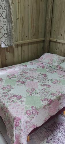 a bed with a pink and green quilt on it at Vista da lagoa in Laguna