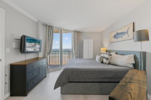 Un dormitorio con una cama y un televisor y un balcón. en Oceania Plaza 405, en New Smyrna Beach