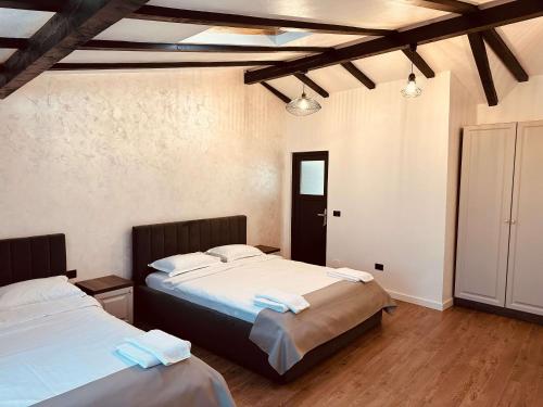two beds in a room with wooden floors at Casa YDA in Horezu